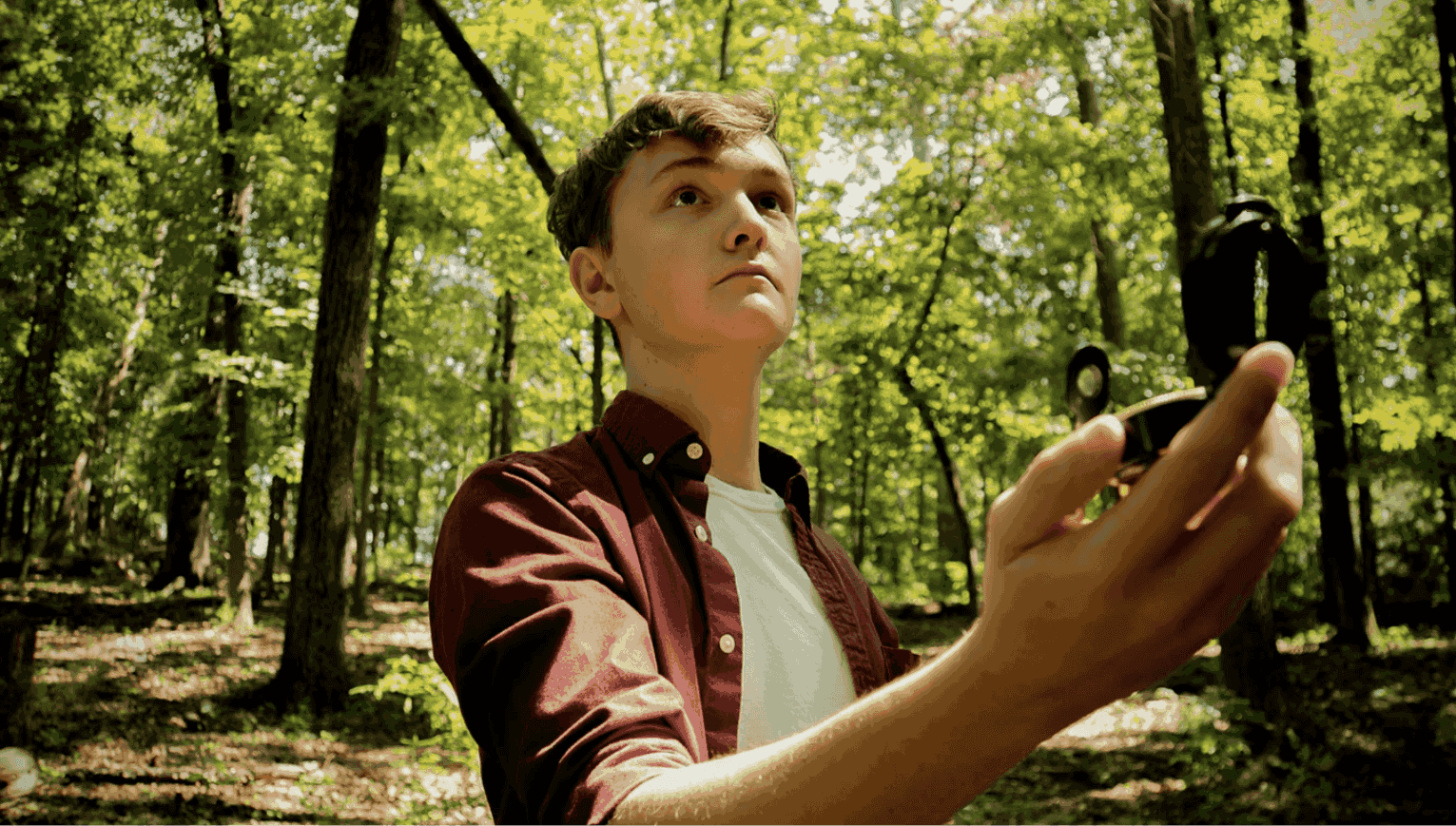 Man in a forest walking around with a compass