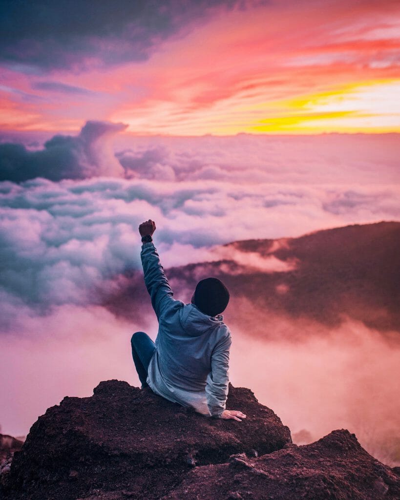 man on top of mountain cheering about cash loans for bad credit
