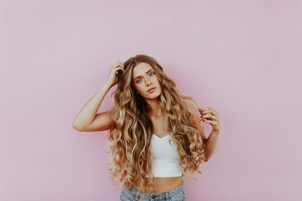 Woman with long hair standing against pink wall thinking about loans for people with bad credit