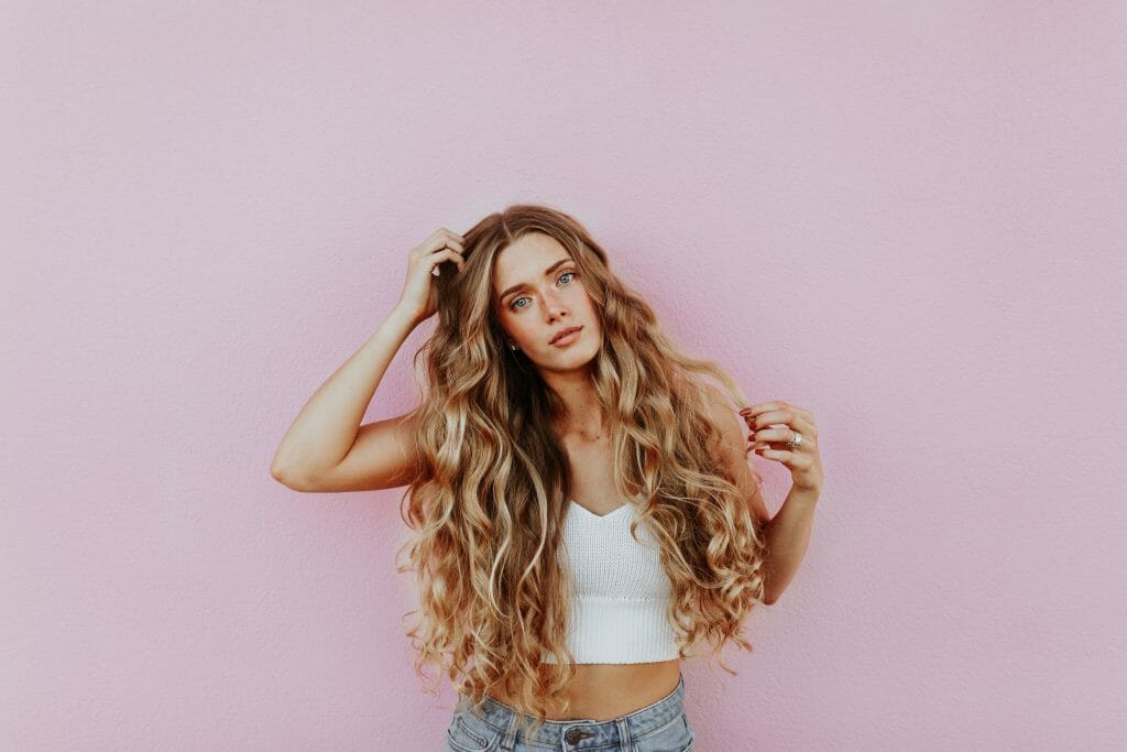 Woman with long hair standing against pink wall thinking about loans for people with bad credit