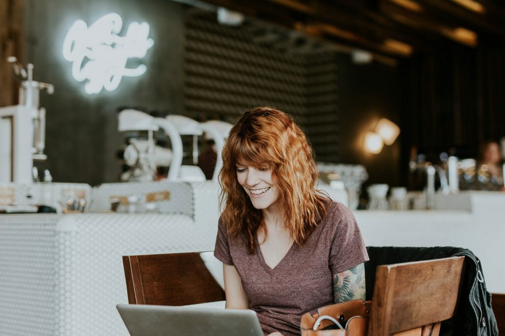Woman in cafe browsing for fast money loans on laptop