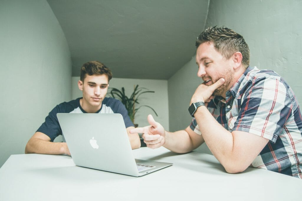 Two men looking at cash loans today on silver laptop