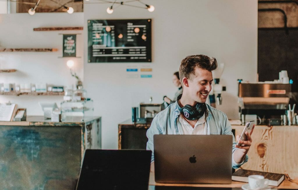 Man smiling in cafe looking at no credit check payday loans Australia on laptop