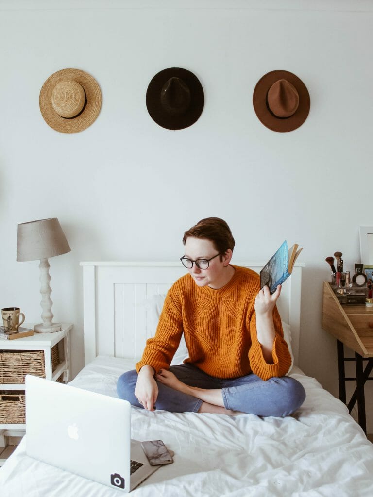 Woman sitting on bed with laptop applying for online payday loans