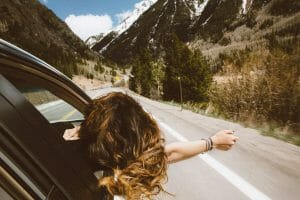 Cheapest car loan woman leaning out car window driving through mountains