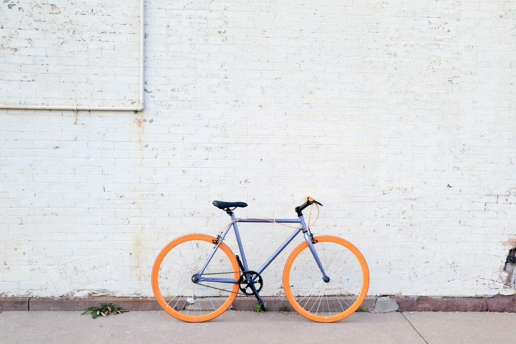 Bike loan bicycle with orange wheels leaning against white wall