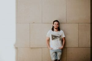 Cheap personal loan man leaning against off white wall