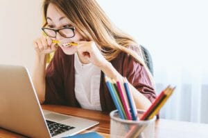 Woman biting a pencil while searching for online loans for Centrelink customers